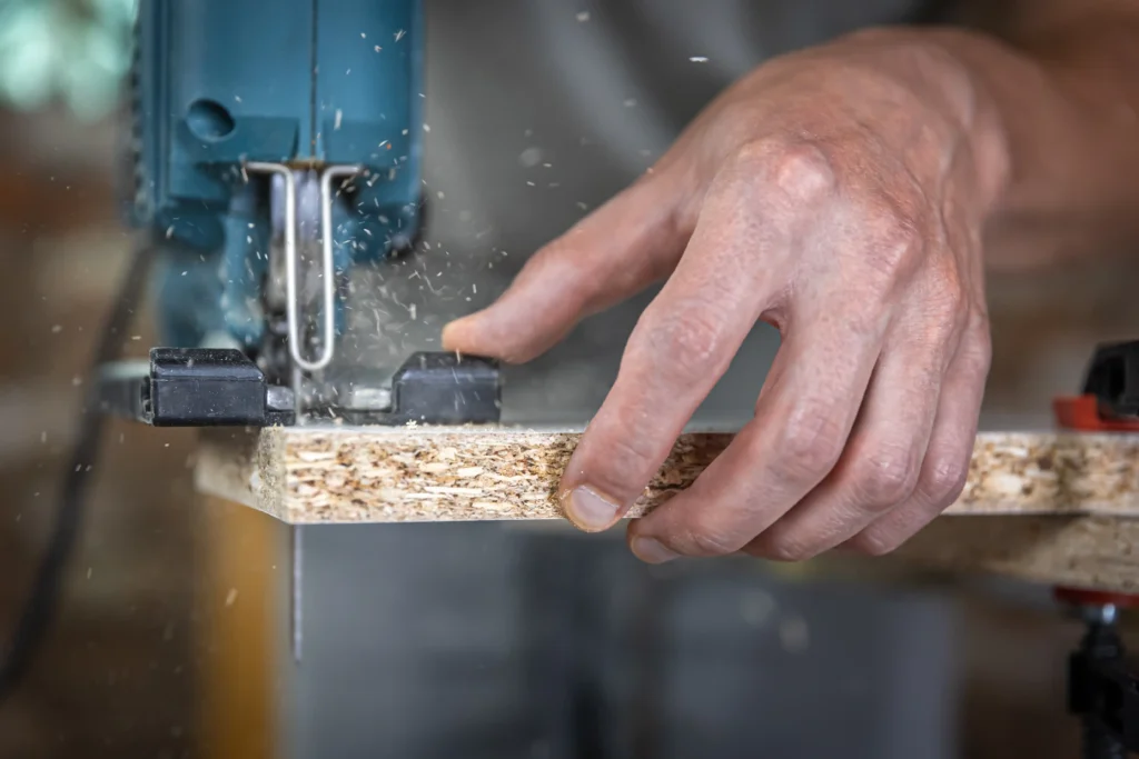 close-up-carpenter-s-hands-process-cutting-wood-with-jigsaw